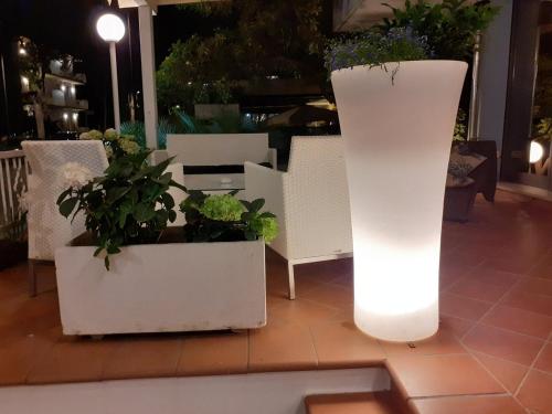 two white planters with plants in them on a floor at Hotel Ambasciata in Cesenatico
