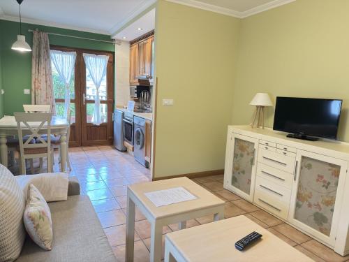 a living room with a couch and a tv and a kitchen at Posada El Corcal de Liébana in Tama