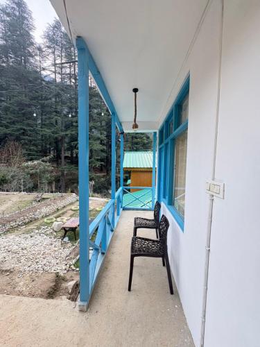 a chair sitting on the porch of a house at Pine Nest Deluxe Rooms in Jibhi