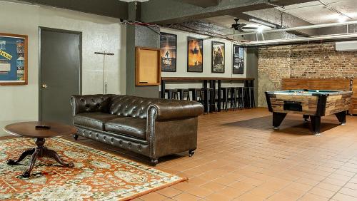 a living room with a leather couch and a pool table at Gardner Hotel & Hostel in El Paso