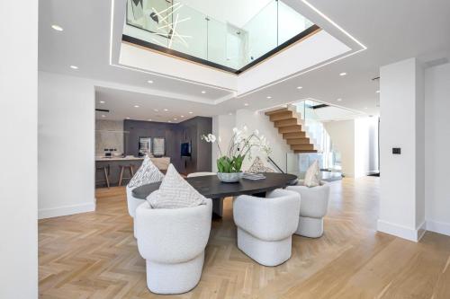 a dining room with a black table and white chairs at Luxe Retreat 5-Bedroom Designer Home Pool & Cinema in Brighton & Hove