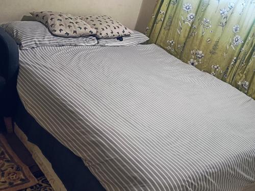 ein Bett mit gestreiftem Bettlaken und einem Kissen darauf in der Unterkunft Private room in Hornchurch London Homestay in Hornchurch