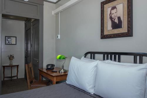 a bedroom with a bed with white pillows and a table at Gardner Hotel & Hostel in El Paso