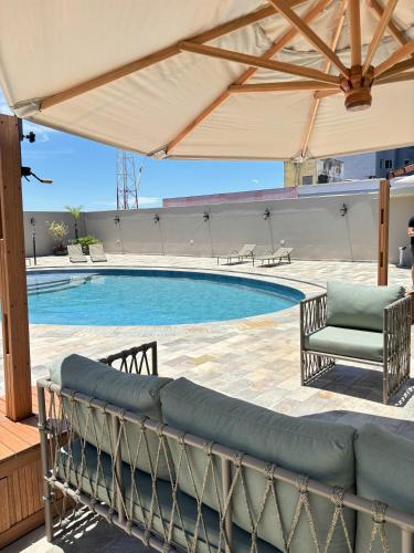 einen Pool mit einem großen Sonnenschirm auf einer Terrasse in der Unterkunft Copas Verdes Hotel in Cascavel