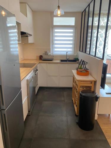 - une cuisine avec des armoires blanches et une poubelle dans l'établissement Bel et moderne appartement à 15 min de Paris, à Houilles