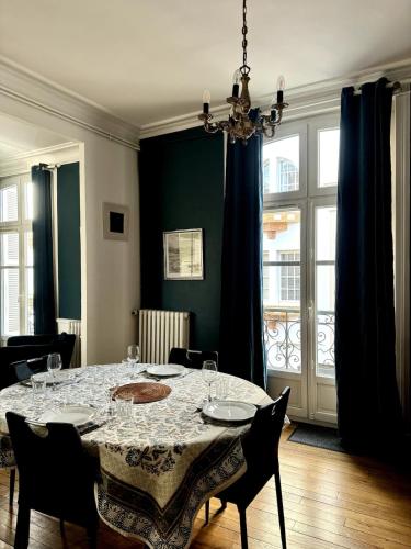 une salle à manger avec une table, des chaises et un lustre dans l'établissement SUPER appartement au coeur de la ville et à 2 pas des plages, à Dinard