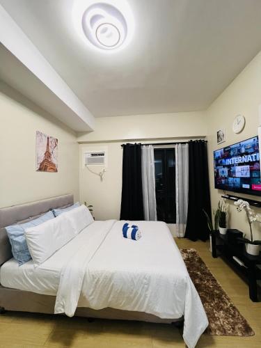 a bedroom with a large white bed and a flat screen tv at VINIA INFINITY STUDIO 4 near MALLS and MRT STATION in Manila
