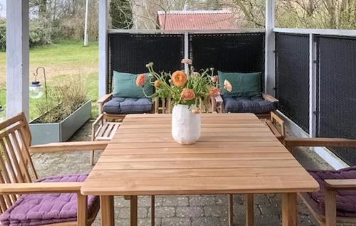 a wooden table with a vase of flowers on a patio at Cozy Apartment In Nordborg in Nordborg