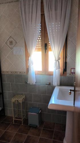 bagno con lavandino e finestra con tende di Casa Maite a Riópar