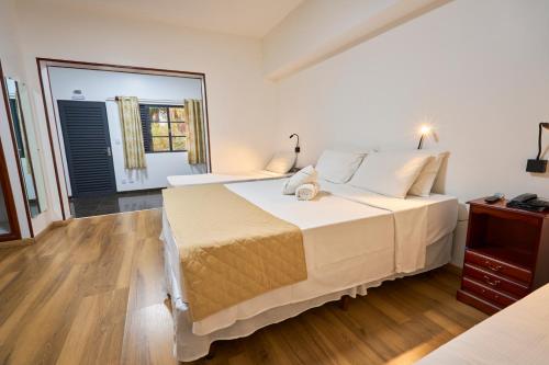 a bedroom with a large white bed and a mirror at SESC POÇOS DE CALDAS in Poços de Caldas