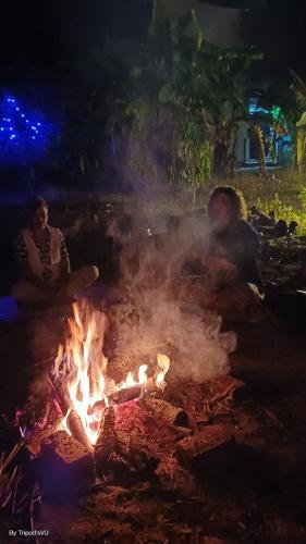 two people sitting around a campfire at night at Healing Home And Hostel Auroville in Puducherry