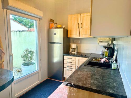 Il comprend une cuisine équipée d'un réfrigérateur en acier inoxydable et une fenêtre. dans l'établissement Bord de mer 60 m - Charmante Maison 5 personnes, à Fouras