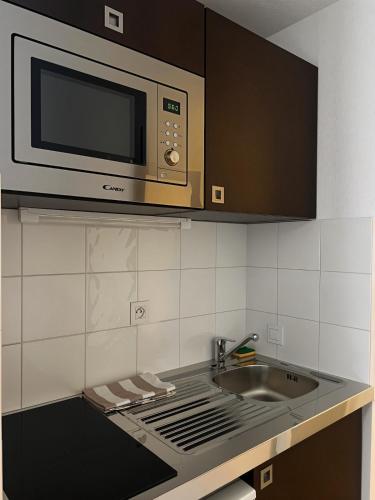 une cuisine avec un micro-ondes et un évier dans l'établissement Studio de 25m2 à proximité immédiate de Paris Expo, Porte de Versailles, à Malakoff
