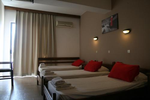 a room with four beds with red pillows at Hotel Platon in Faliraki