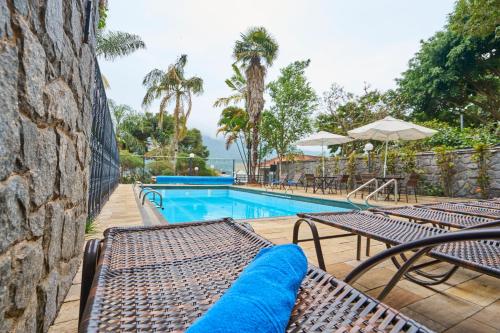 a swimming pool with two chairs and a table at SESC POÇOS DE CALDAS in Poços de Caldas