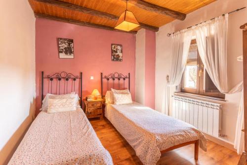 two beds in a room with pink walls at Casa Rural El Cencerro in Villamanrique de Tajo