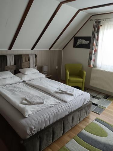 a bedroom with a bed and a green chair at Patrícia Panzió in Bük