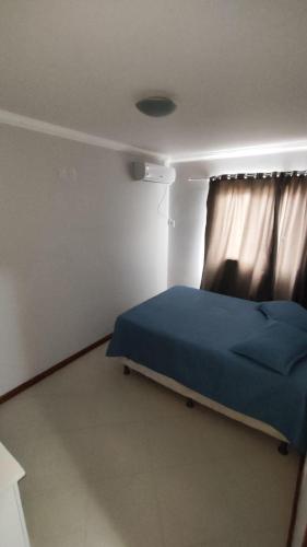 a bedroom with a blue bed and a window at Half Beach Apartment - Itapema in Itapema