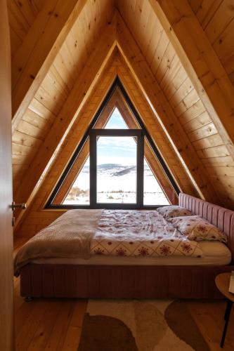 a bed in a room with a large window at Vikendica miRAJ Manjaca in Gornje Ratkovo