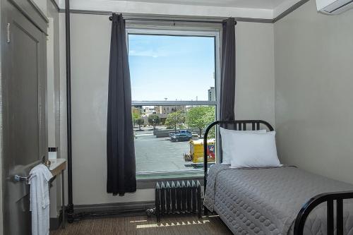a bedroom with a bed and a window with a view of a street at Gardner Hotel & Hostel in El Paso