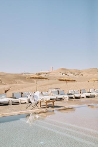 a group of chairs and umbrellas on a beach at Alkamar Camp Agafay in El Karia