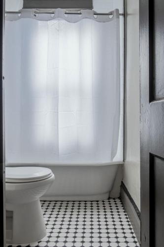 a bathroom with a toilet and a shower curtain at Gardner Hotel & Hostel in El Paso