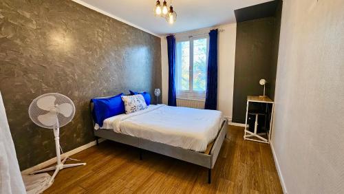 - une chambre avec un lit doté d'oreillers bleus et d'un ventilateur dans l'établissement Chambre privée dans logement partagé, Moon Ray Paris & Stade de France, à Stains