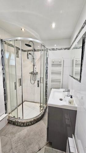 une salle de bain blanche avec une douche et un lavabo dans l'établissement Chambre privée dans logement partagé, Moon Ray Paris & Stade de France, à Stains