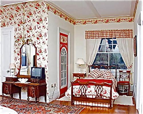 a bedroom with a bed and a mirror and a television at Whistler's Inn in Lenox