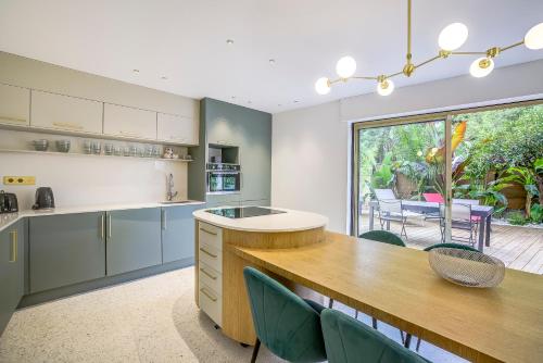 une cuisine avec une table et des chaises ainsi qu'une grande fenêtre dans l'établissement Perle rare au coeur de la pinede, à Antibes