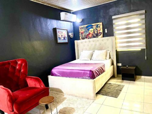a bedroom with a bed and a red chair at Budget Friendly Ample 2bedroom 10-min 4rm Airport in Lagos