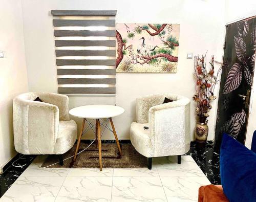two chairs and a table in a living room at Budget Friendly Ample 2bedroom 10-min 4rm Airport in Lagos