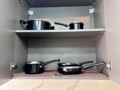 two pots and pans on a shelf in a kitchen at Pebbles Nest in Kwabenya