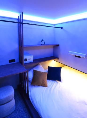 a bedroom with a white bed with a blue light at The Hyve Capsule Amsterdam in Amsterdam