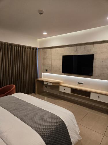 a hotel room with a bed and a flat screen tv at MoonBasa Boutique Hotel and Spa Infopark , Kakkanad in Cochin