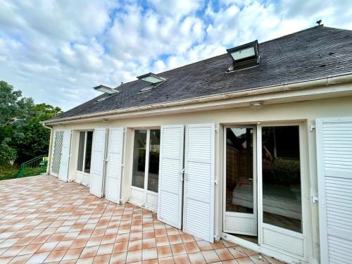 a house with white doors on a patio at Villa Saint Antoine, vue mer à 60m de la plage in Réville