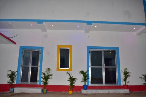 a white building with blue windows and palm trees at TabTrips Laxmi Resort in Bāghmundi