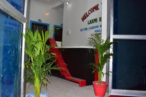 a lobby with potted plants and a red bench at TabTrips Laxmi Resort in Bāghmundi