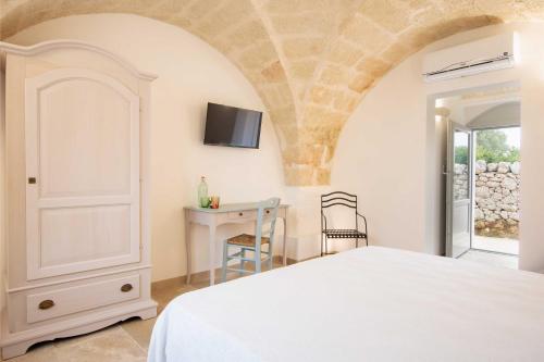a bedroom with a bed and a desk and a tv at Tenuta Mogavero in Torre Canne