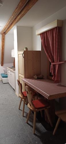 a table and chairs in a room with a table and a curtain at HIŠA MARGIT, Studio APARTMA in Rateče