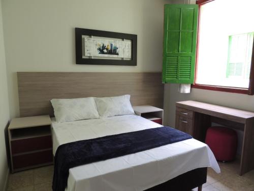 a bedroom with a bed and a desk and windows at Hotel Continental - Próximo ao Mercado Central, Mercado Novo e a Rodoviária in Belo Horizonte