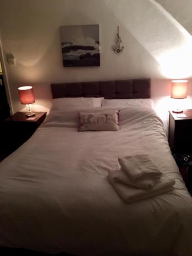 a large white bed with two towels on it at Harbour view cottage, clovelly in Clovelly