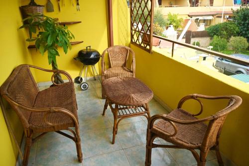 three rattan chairs and a table on a balcony at Casa Pura Vida in Quartu SantʼElena