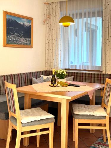 a wooden table with two chairs and a bottle of wine at Haus Gamper-Haselwanter in Tarrenz