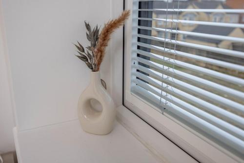 a white vase sitting on a window sill with a plant in it at 1 Bedroom Flat Near Bradford With Free Parking in Saltaire