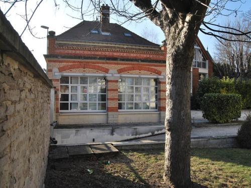 une maison en briques avec un arbre devant elle dans l'établissement Gîte La Tour Boileau, à Troyes