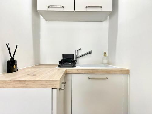a kitchen with white cabinets and a sink at Lou Miradou 2 - Vieux village médiéval, Cosy, Clim, 2 personnes in Miramas