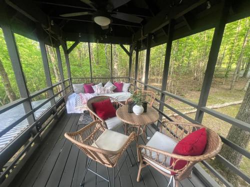 a screened in porch with chairs and a couch at Rabbits Run Mountain Retreat in Mentone