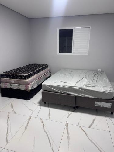 two twin beds in a room with white walls at Nosso Recanto Alicia e Miguel in Ibiúna