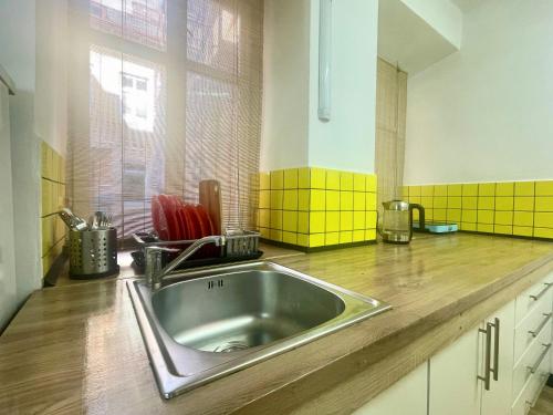 a kitchen with a stainless steel sink and yellow tiles at Апартаменти в центрі старого Львова in Lviv